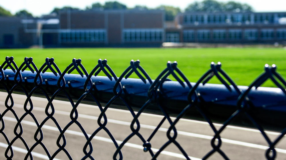 Chain link fence around a running track. Madison fencing company fence contractors Madison, Wisconsin ballfield baseball field softball field football field complex pickle ball courts basketball tennis courts track peewee elementary junior high high school college professional community chain link wood ornamental backstop dugouts outfield batter's eye 